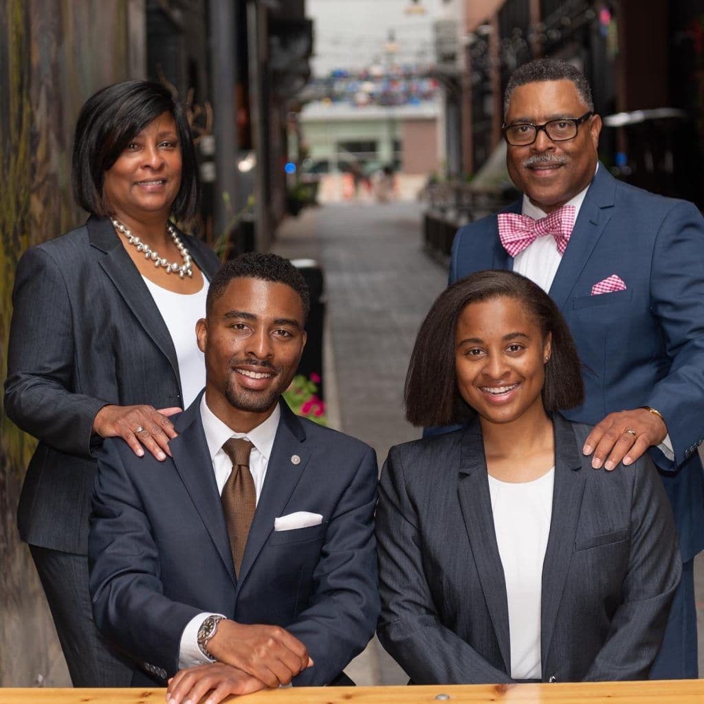 Attorney Arnold Reed, Attorney Harolyn D. Beverly, and Attorney Arnold Reed II posing in a family photo with the soon to be practicing daughter of Arnold Reed and Harolyn D. Beverly