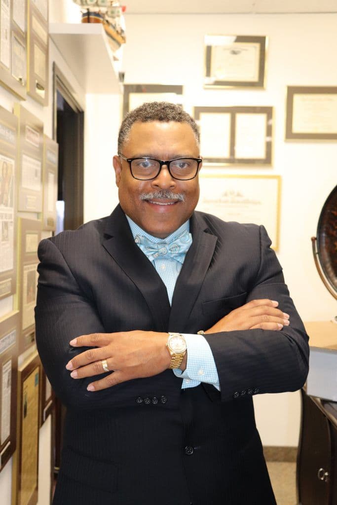 Attorney Arnold Reed Posing in his office in front of a hallway full of plaques