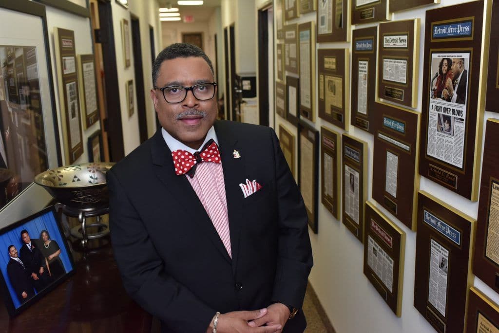 Attorney Arnold Reed Posing in his office in front of a hallway full of plaques, awards, and press clippings